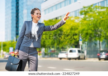 Happy business woman in office district catching taxi