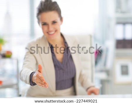 Closeup on happy business woman stretching hand for handshake in office
