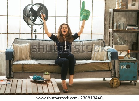 Portrait of football fan woman watching tv in loft apartment and rejoicing