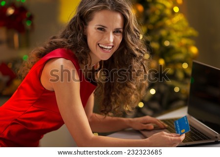 Portrait of happy young woman with credit card using laptop
