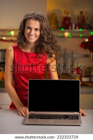 Portrait of smiling young woman showing laptop blank screen