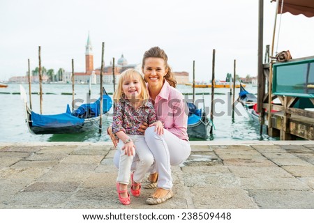 Portrait of smiling mother and baby on grand canal embankment in venice, italy