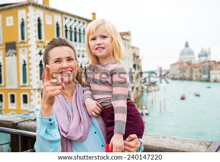 Baby girl and mother poiting while standing on bridge with grand canal view in venice, italy