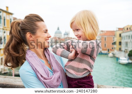 Portrait of happy mother and baby girl on bridge with grand canal view in venice, italy