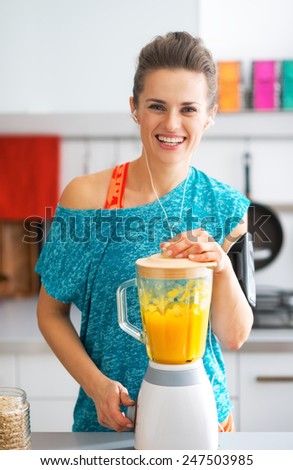 Portrait of happy fitness young woman making pumpkin smoothie in kitchen