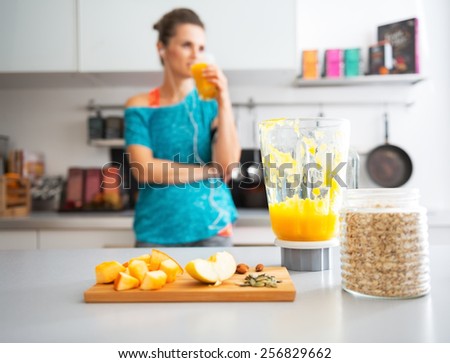 Close-up on pumpkin smoothie and ingredients on table and fitness young woman in background