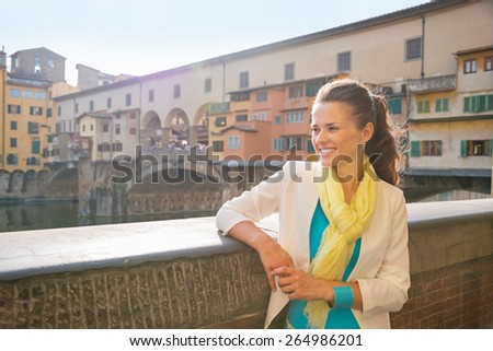 Happy young woman looking into distance near ponte vecchio in florence, italy