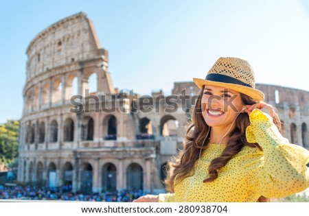 Nothing like listening to some tunes while being a tourist. A happy, smiling woman stands near the Colosseum, readjusting her earbuds.