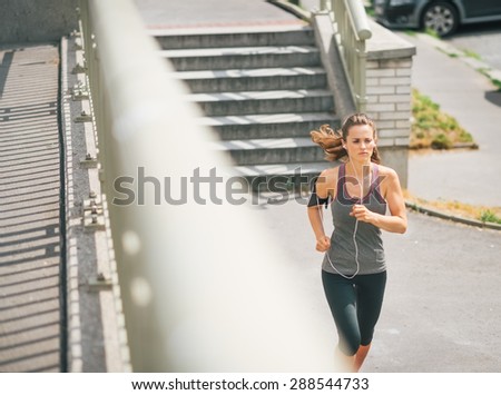 One step at a time, and the goal is reached. A woman jogger is concentrating on the path ahead, focused on achieving her goal.