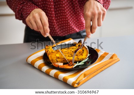 In closeup, an elegant woman\'s hands holding cutlery are picking food up or cutting it.