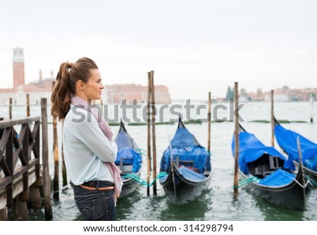 A woman stands, dreaming of times past, listening to the sound of the water lapping against the moored gondolas.
