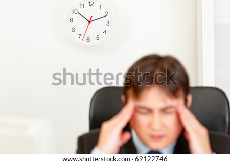 Stressed business man  aware of approaching deadline. Focus on clock