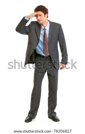 Concentrated young  businessman holding  his hand at forehead and looking forward in future isolated on white