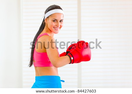 Smiling pretty fit girl in boxing gloves