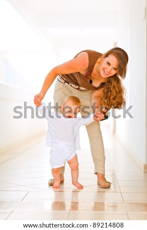 Happy mom helping baby to walk