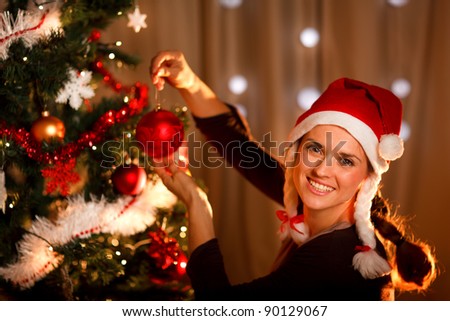 Beautiful woman hanging toy on Christmas tree