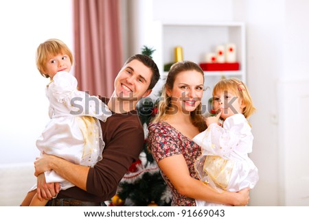 Family portrait of mother father and twins daughter near Christmas tree