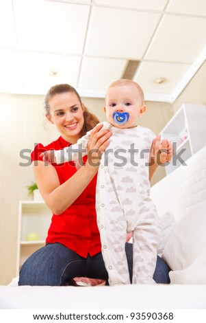 Smiling mother helping baby learn to walk