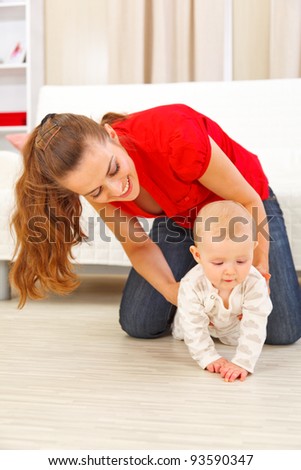 Mother helping cheerful baby learn to creep