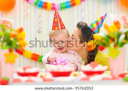 Mother kissing her happy while baby checking present
