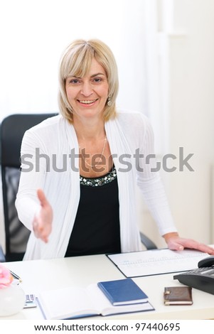 Smiling senior business woman stretching hand for handshake