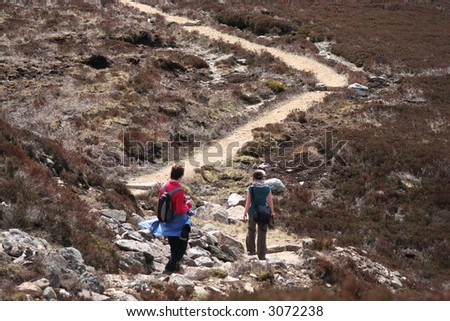 two women walking along path in countryside in summer