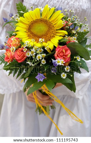 country styled wedding bouquet of yellow sun flower and small colorful flowers at girl\'s hands