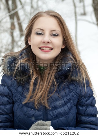 young woman with snowball in blue coat outdoors in snow garden