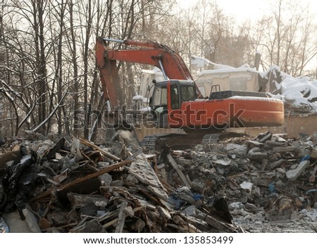 Excavator works on the pile of debris