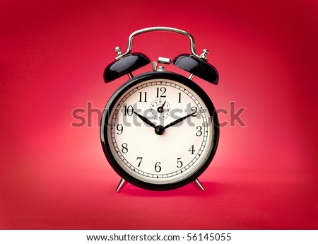 Alarm clock on a red background. Studio shot