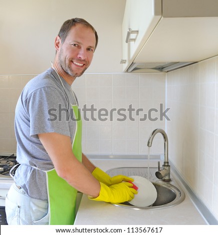 Smiling man washing dish in the kitchen