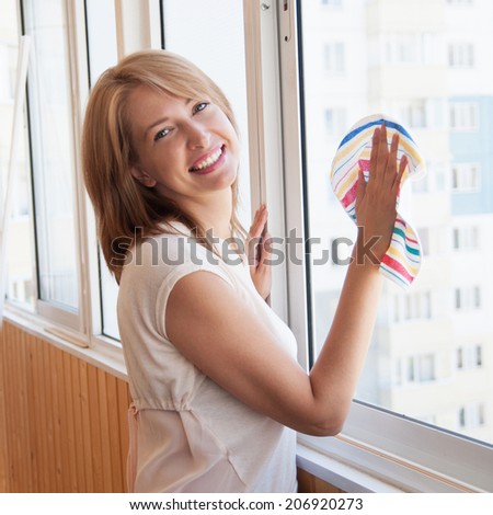 Happy woman washes window in the new apartment