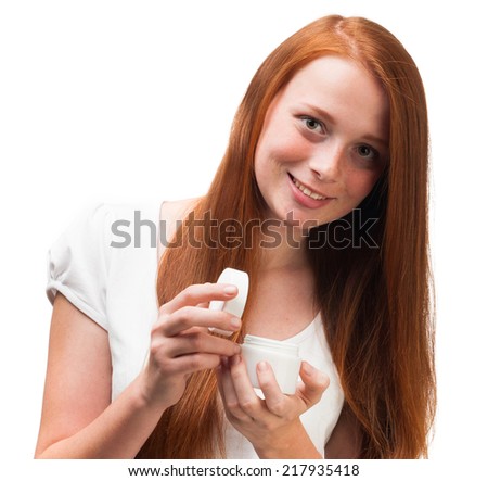 Young red-haired girl holding a package with a face cream. Isolated on white background