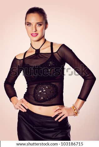 beautiful woman with pink lipstick wearing a mesh fashion top and a leather black skirt on pink background.
