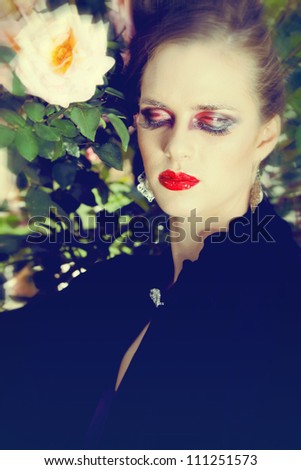 beautiful woman with grunge dramatic makeup outside wearing vintage velvet cape and expensive jewelry
