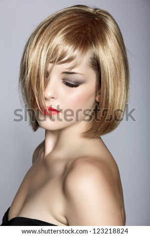 beautiful young woman with short blond hair in a bob wearing red lipstick on studio background