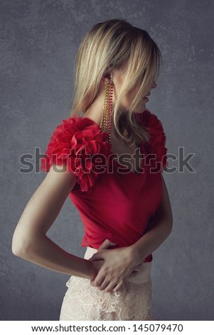 beautiful blond woman with messy hair wearing ruffled red top and lace skirt on grunge studio background