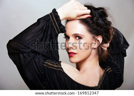 Beautiful woman with brown hair braided in upstyle wearing black off shoulder dress on studio background