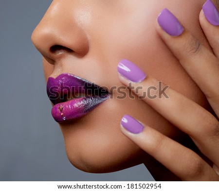 Close-up of woman\'s mouth with dark fashion purple lipstick with ombre effect. Hand with purple nailpolish touching tanned face