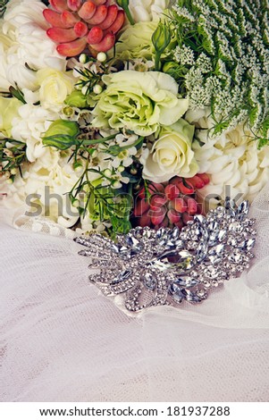Fresh white and green flower bouquets in romantic style on veil with bridal jewelry