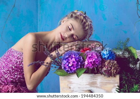 Dreaming portrait. Beautiful blond woman with braid hairstyle and natural makeup. Wearing pink bohemian sequin dress. Against blue grunge background