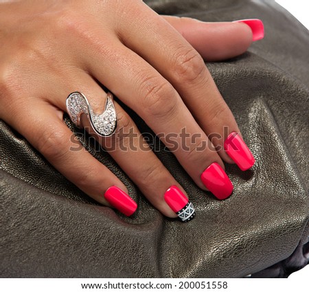 closeup of the woman\'s hand wearing luxury ring, pink nail art manicure on bronze leather bag background