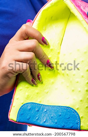 closeup of the woman\'s hand with red art manicure, holding pink neon handbag isolated on white studio background