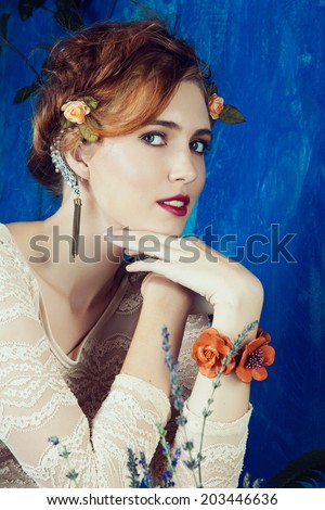 portrait of a beautiful woman with red hair in braided hairstyle and flowers in her hair. wearing leather orange bracelet grunge painted background