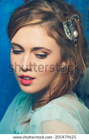 Romantic portrait of a young woman with braid hairstyle and luxury hair accessories on blue grunge texture background