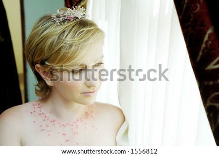 young bride in pink tiara looking out of the window