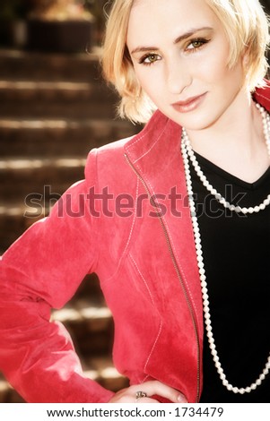 Blond business-woman with short hair in red leather jacket and pearls