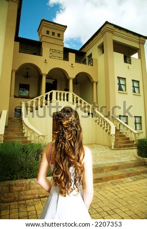 Bride in A-line dress and dark long curly hair standing with her back on the background of a Tuscan house