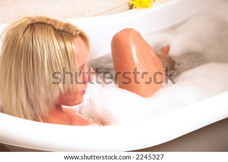 Young woman sitting in a bubble bath with her knee exposed