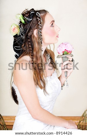 Beautiful young bride with long brown hair in wedding dress holding a small antique flower bouquet with hair braided in Renaissance style